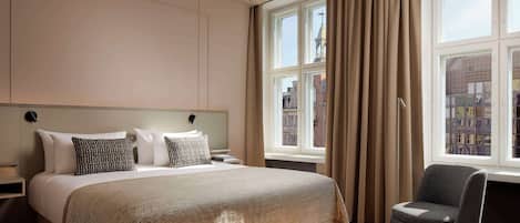A hotel room with a large bed, a chair, and a window with curtains.