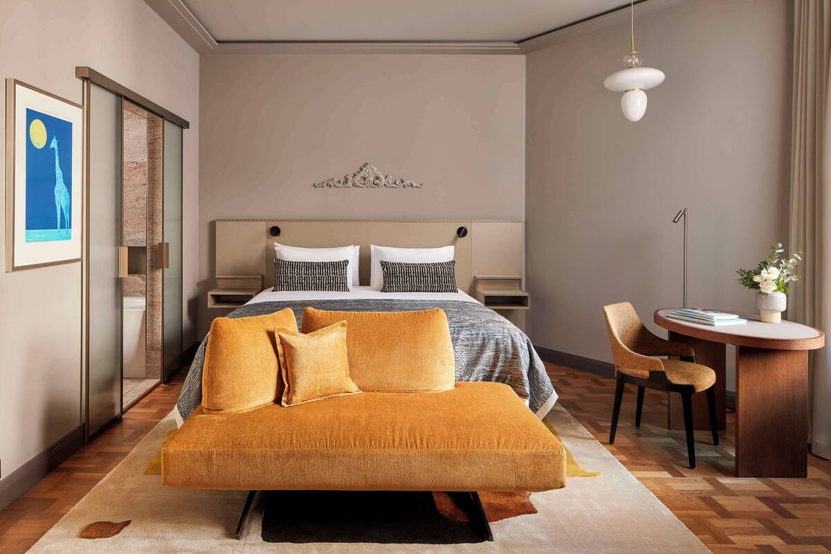 Ein modernes Hotelzimmer mit einem großen Bett, einer Couch, einem Schreibtisch und einem Stuhl.