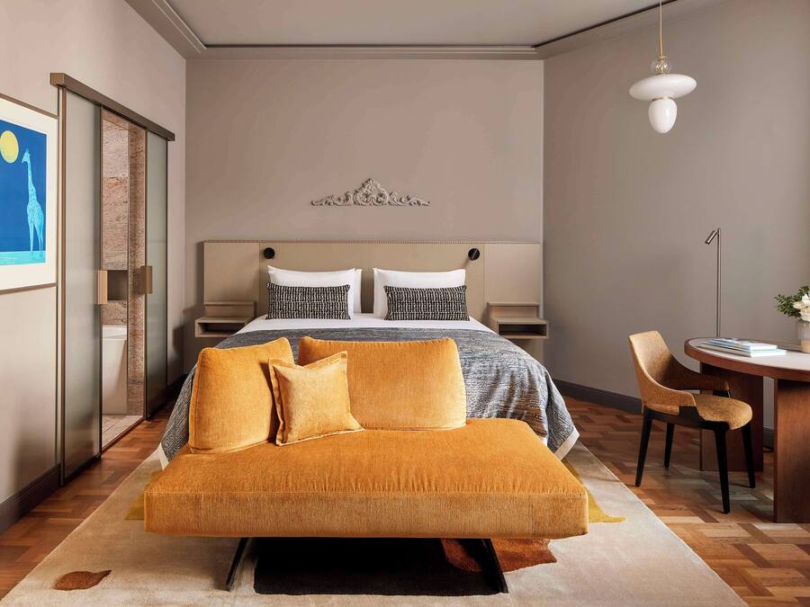 Ein modernes Hotelzimmer mit einem großen Bett, einer Couch, einem Schreibtisch und einem Stuhl.