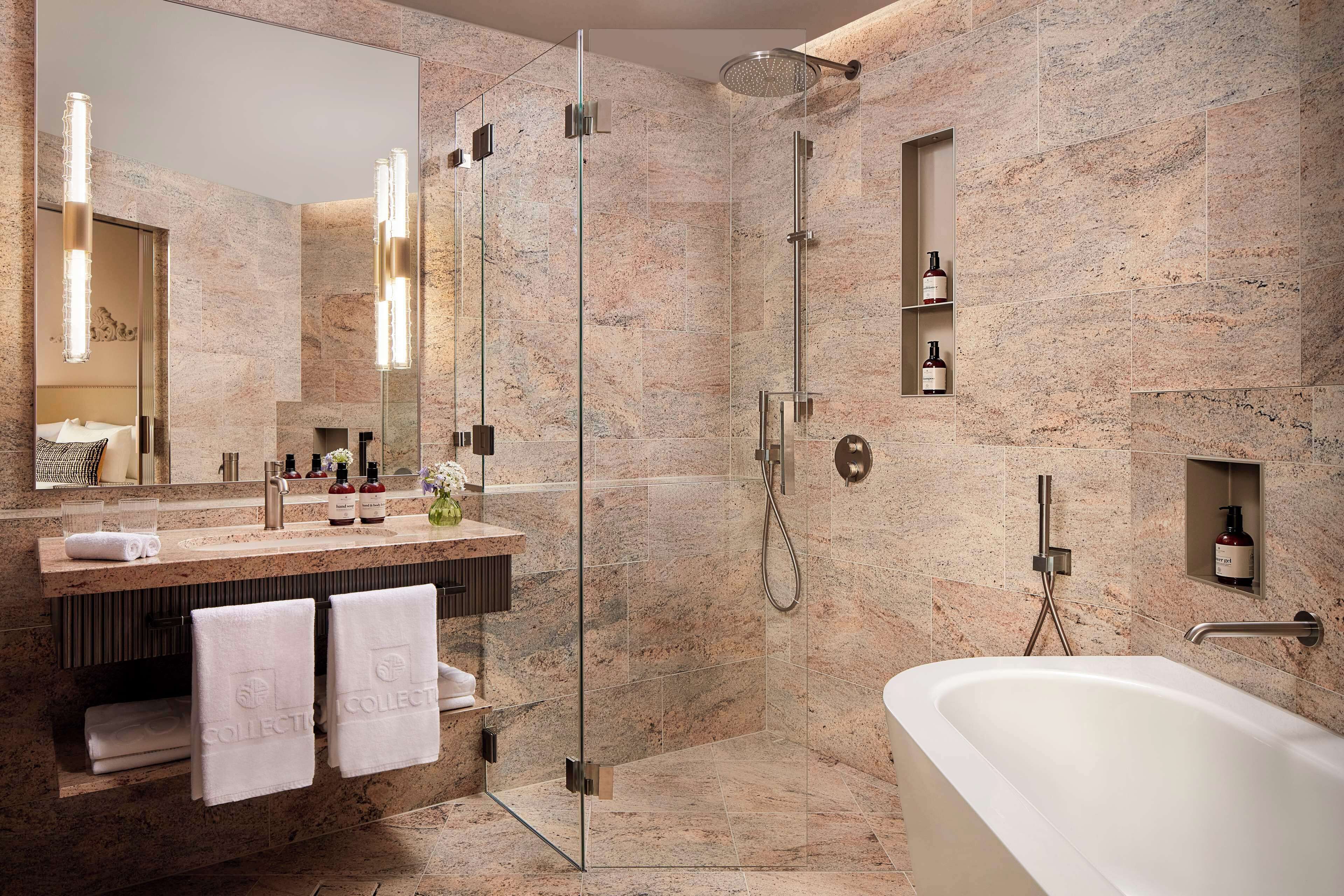 A modern bathroom with a glass-enclosed shower, a freestanding bathtub, and a vanity with a mirror and towel rack.