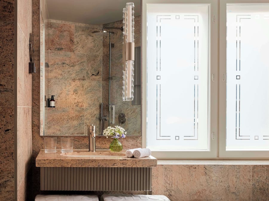 A bathroom with a granite countertop, a mirror, a glass shower enclosure, and frosted glass doors.