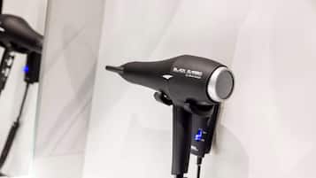 Un sèche-cheveux doté d’un écran numérique et d’un cordon d’alimentation, fixé à un mur blanc.