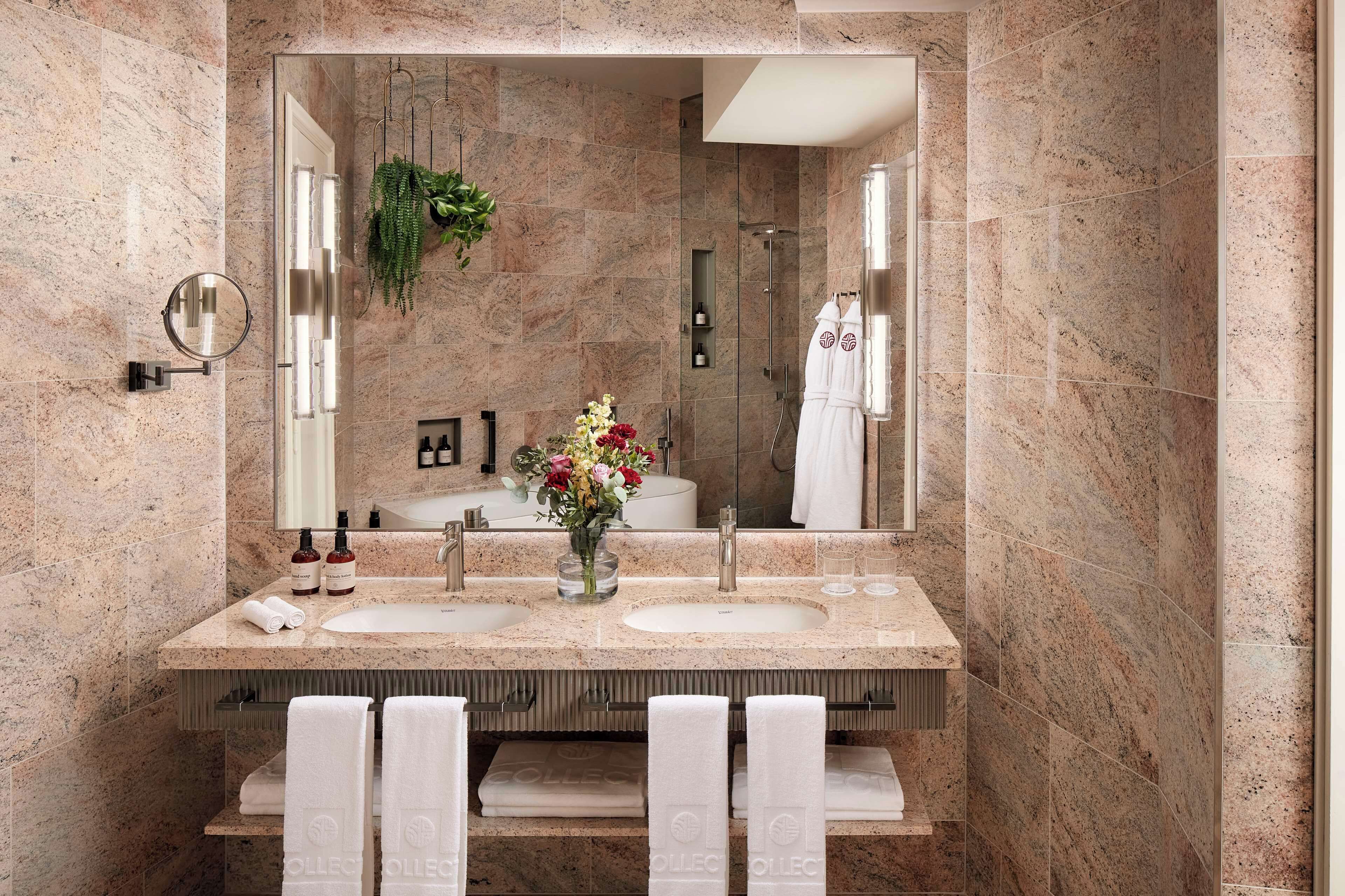 Un baño moderno con dos lavamanos, un espejo grande y una ducha.
