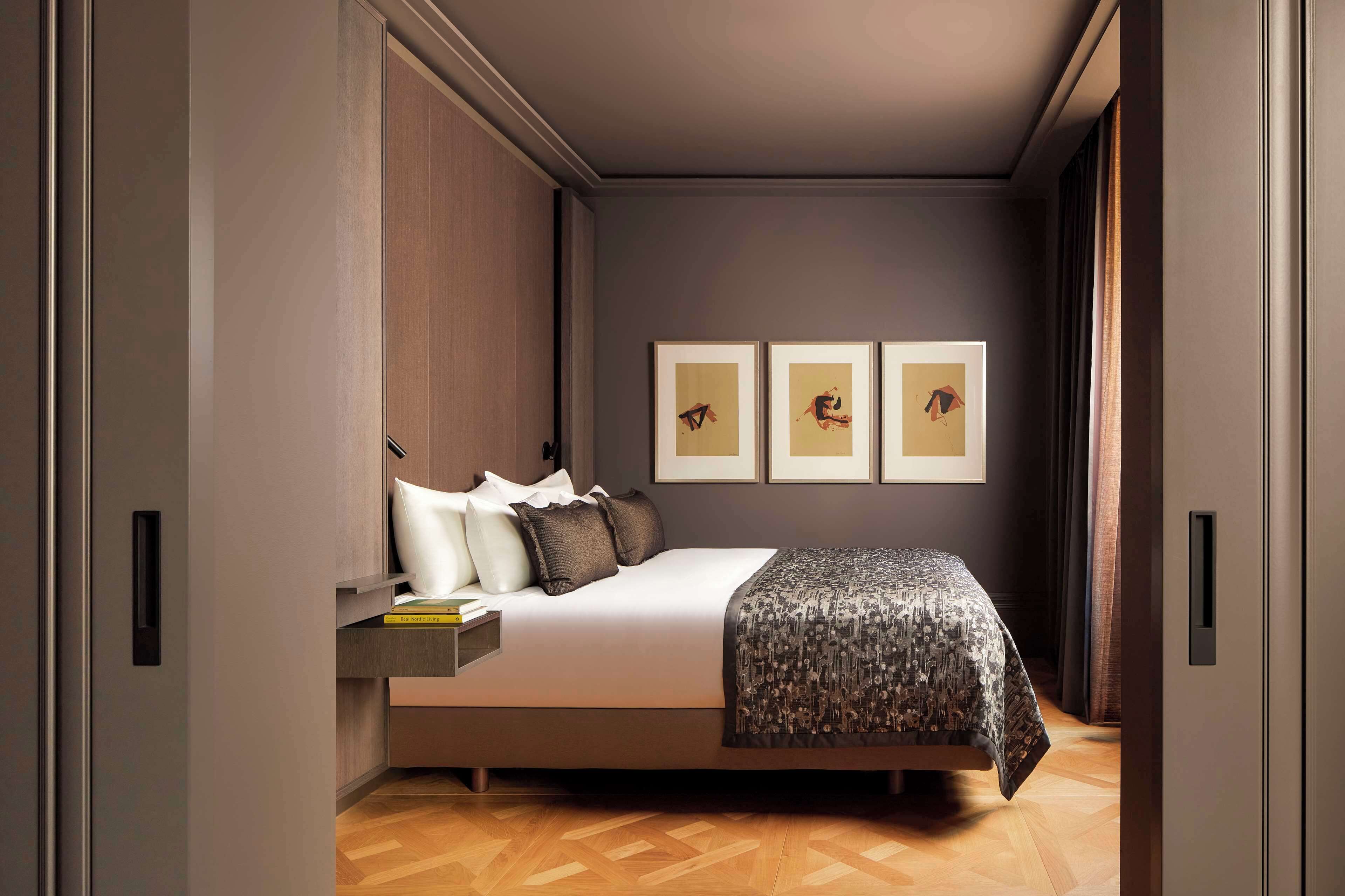 A modern bedroom with a bed, bedside tables, and framed artwork on the wall.
