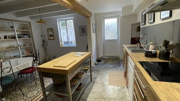 Een moderne keuken met houten aanrecht, een ingebouwde oven en een eethoek met tafel en stoelen.