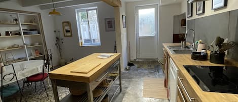 Una cocina moderna con mostradores de madera, horno empotrado y comedor con mesa y sillas.