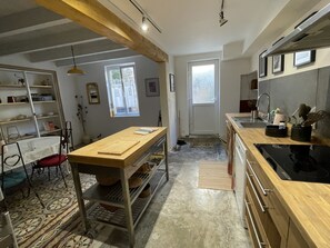A modern kitchen with wooden countertops, a built-in oven, and a dining area with a table and chairs.