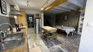 A kitchen with a stainless steel refrigerator, wooden countertops, and a dining area with a patterned rug.