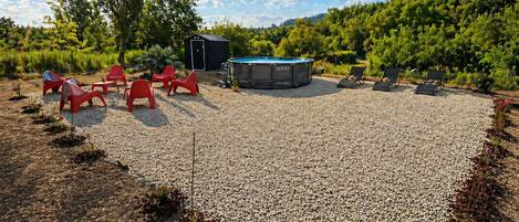 A pool area with a hot tub, red chairs, and a small shed.