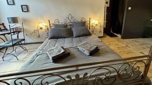 A bedroom with a metal bed frame, a bedside table with a lamp, and a chair.