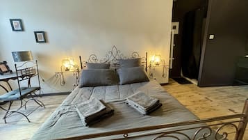 A bedroom with a metal bed frame, a bedside table with a lamp, and a chair.