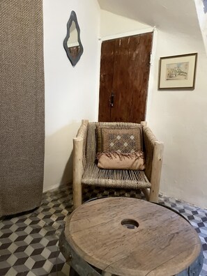 A room with a checkered floor, a woven chair with a patterned cushion, a wooden table with a hole in the center, a wooden door, and a framed picture on the wall. - spacious village house with terrace & pool (TAURIZE)