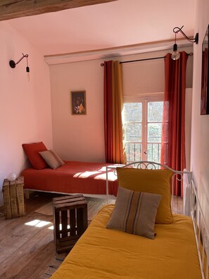 Ein Zimmer mit einem Bett, einem kleinen Tisch und einem Fenster mit Vorhängen.