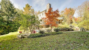 A large house with a stone chimney, surrounded by a well-maintained lawn and trees with autumn leaves. - Winhall Home w/ Deck + Views, 6 Mi to Ski Slopes! (Winhall)