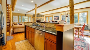A spacious kitchen with wooden beams, a stone fireplace, and large windows. - Winhall Home w/ Deck + Views, 6 Mi to Ski Slopes! (Winhall)