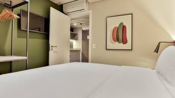 A hotel room with a bed, a wardrobe, a mirror, and a wall-mounted artwork.
