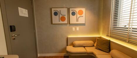 Una habitación moderna con un sofá, una alfombra pequeña y dos obras de arte abstracto en la pared.
