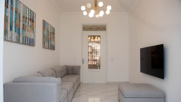 A modern living room with a sectional sofa, a small ottoman, a flat-screen TV, and abstract art on the walls. - Casa Bianca (Panama City)