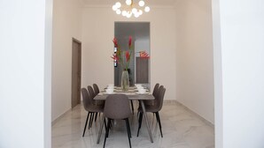 A dining area with a marble floor, a modern chandelier, and a vase with red flowers on the table. - Casa Bianca (Panama City)