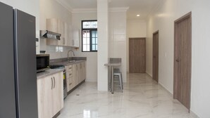 A modern kitchen with a stainless steel refrigerator, granite countertop, and wooden cabinets. - Casa Bianca (Panama City)
