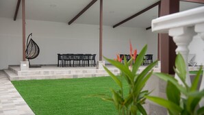 A covered outdoor area with artificial grass, a seating arrangement, and a decorative chair. - Casa Bianca (Panama City)