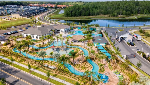 A resort with a large swimming pool, multiple buildings, and a road nearby.