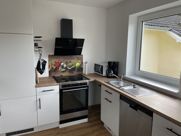 A modern kitchen with white cabinets, a stainless steel stove, a microwave, and a dishwasher.