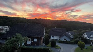 Asuinalue, jossa on taloja, asfaltoitu ajotie ja kumpuileva tausta.
