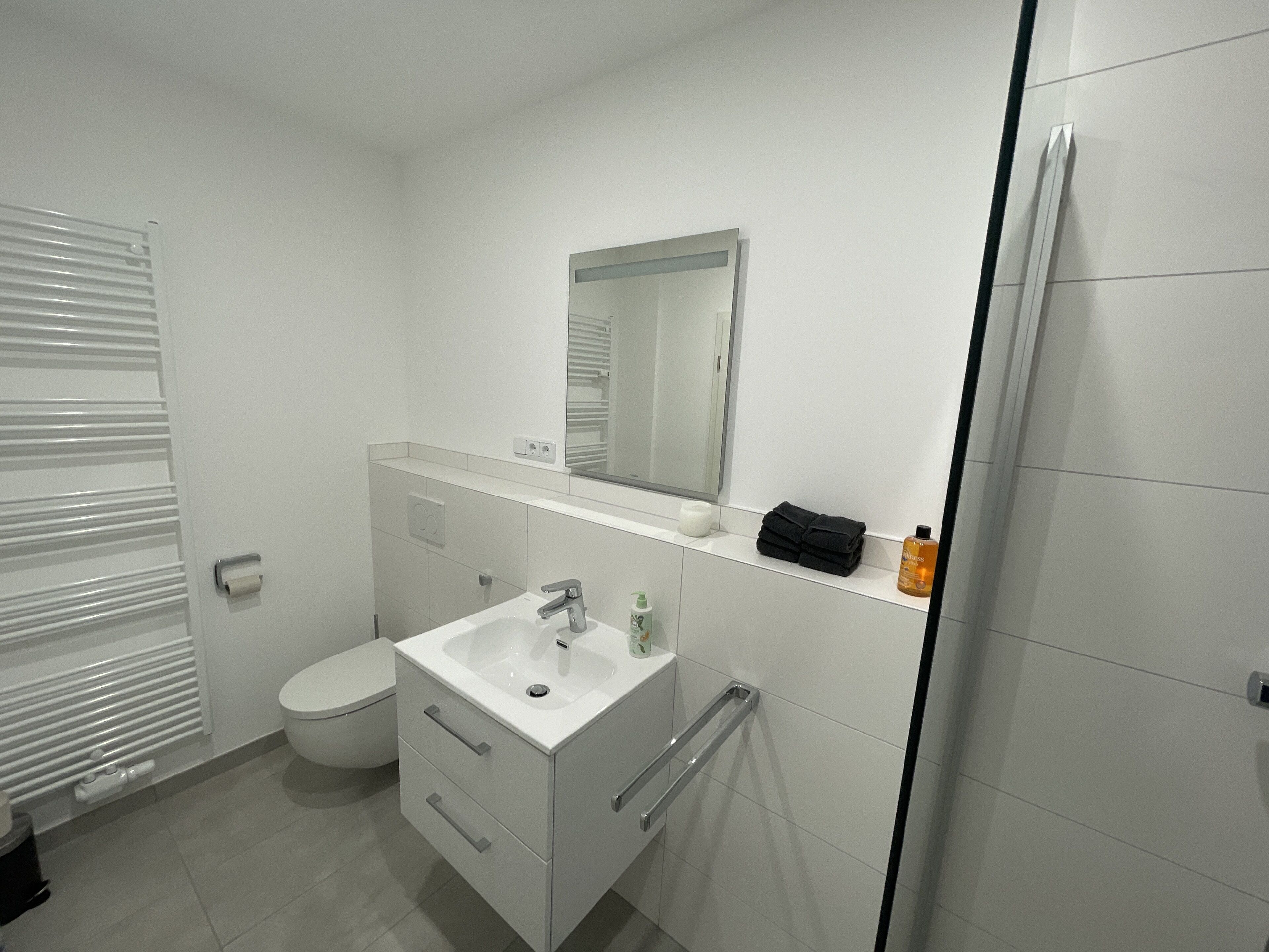 Ein modernes Badezimmer mit Toilette, Waschbecken und Spiegel.