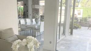 A modern living room with a white sofa, a glass coffee table, and a decorative vase with white flowers. - JC’s Modern Paradise (Chula Vista)
