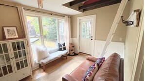 A cozy living room with a bench, a sofa, a cabinet, and a door.
