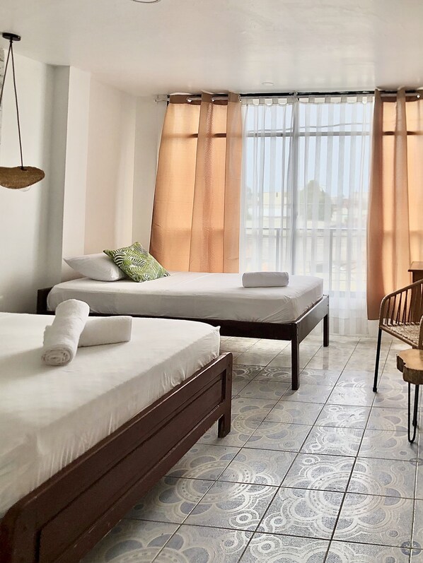 Habitación de hotel con dos camas, una mesita pequeña y una silla.