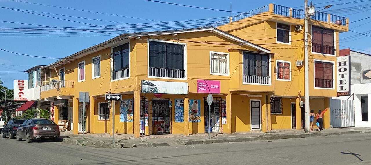 Um edifício amarelo com várias placas, incluindo 'HIELCUB' e 'HOTEL'.