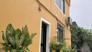 A yellow building with a balcony, potted plants, and a security camera. - Hotel playas (Pedernales)
