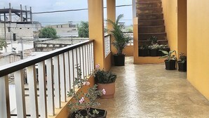 A balcony with potted plants, a railing, and a staircase leading to an upper level. - Hotel playas (Pedernales)