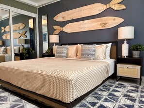 Un dormitorio con una cama grande, dos mesitas de noche, un espejo y decoraciones de peces de madera en la pared.