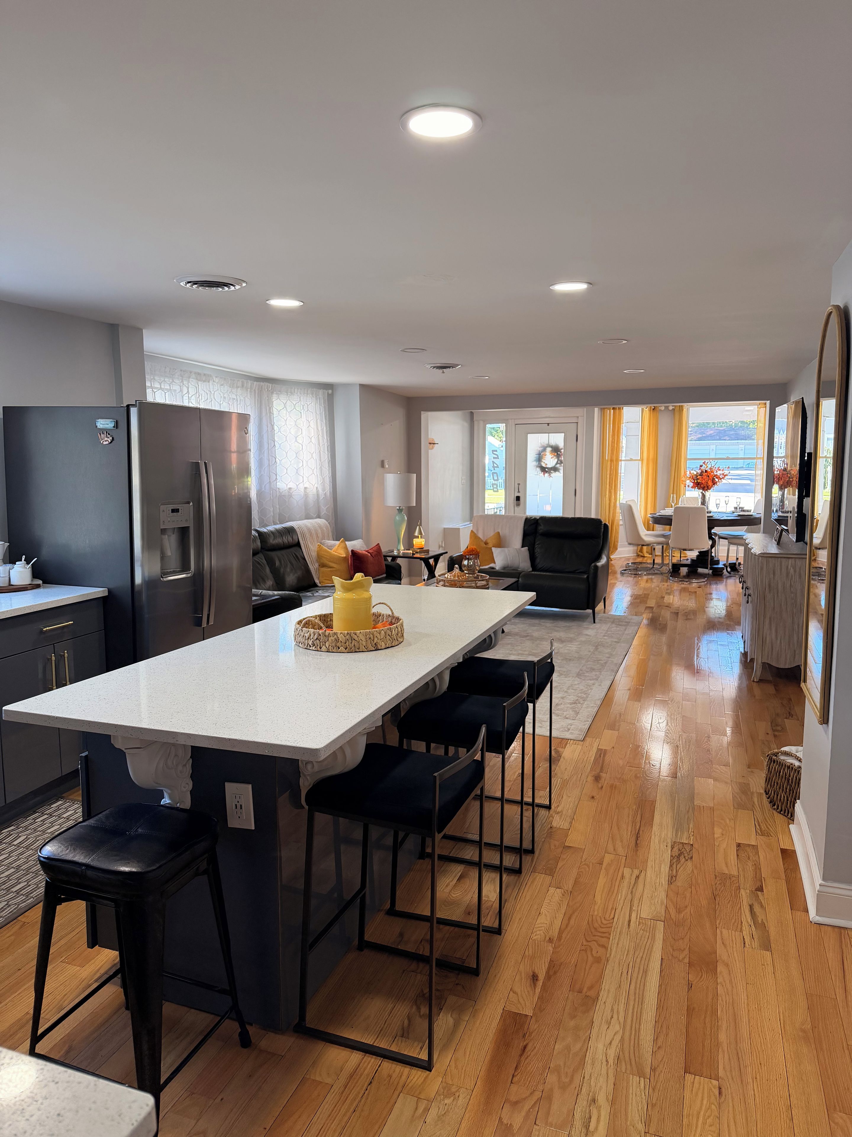 A modern kitchen with a central island, bar stools, and a dining area with a view.