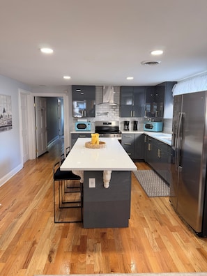 A modern kitchen with a central island, stainless steel appliances, and dark cabinetry. - Colonial Oasis of Peace 5 Guest (Utica)