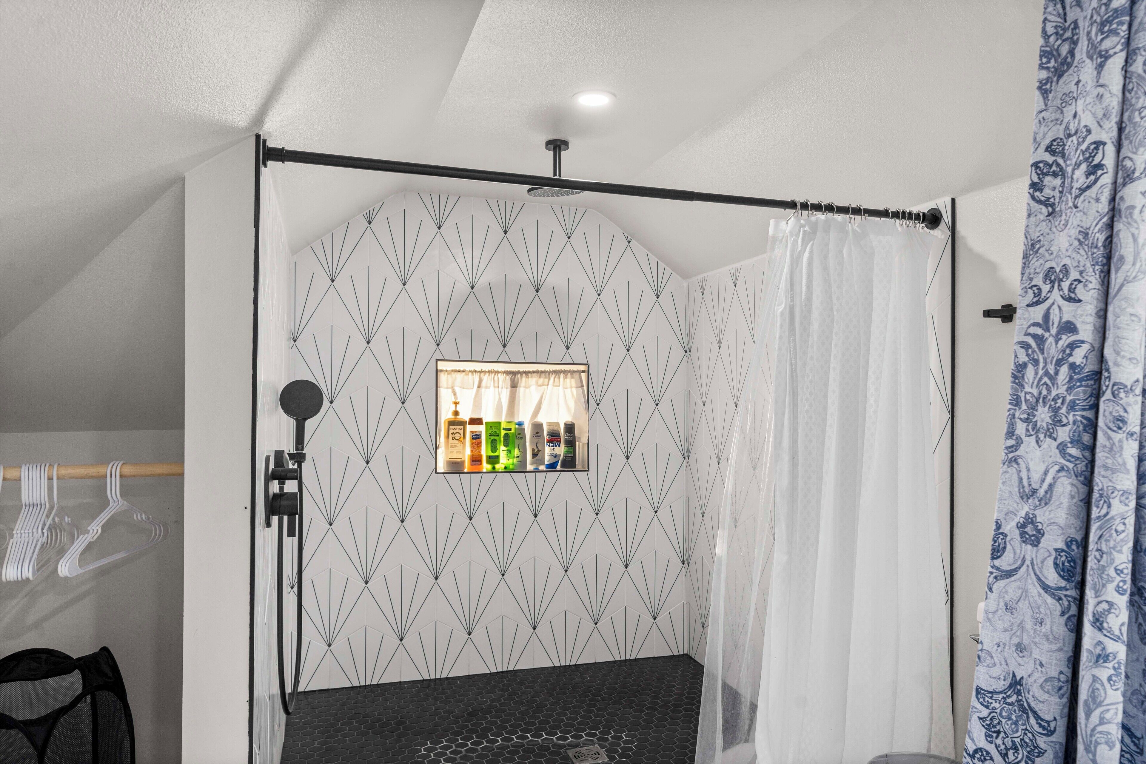 A bathroom with a shower area, a towel rack, and a mirror.