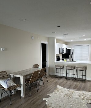 Enjoy a spacious living area with a dining table, kitchen with stainless steel appliances, and a cozy adjacent room.