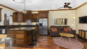 A modern kitchen with wooden cabinets, a central island, and a built-in microwave. - Condo in the Heart of Douglas - Chef's Kitchen (Douglas)