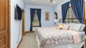 A bedroom with a bed, a ceiling fan, a window with curtains, and a wall-mounted TV. - Condo in the Heart of Douglas - Chef's Kitchen (Douglas)