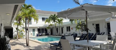 A poolside area with lounge chairs, umbrellas, and a swimming pool.