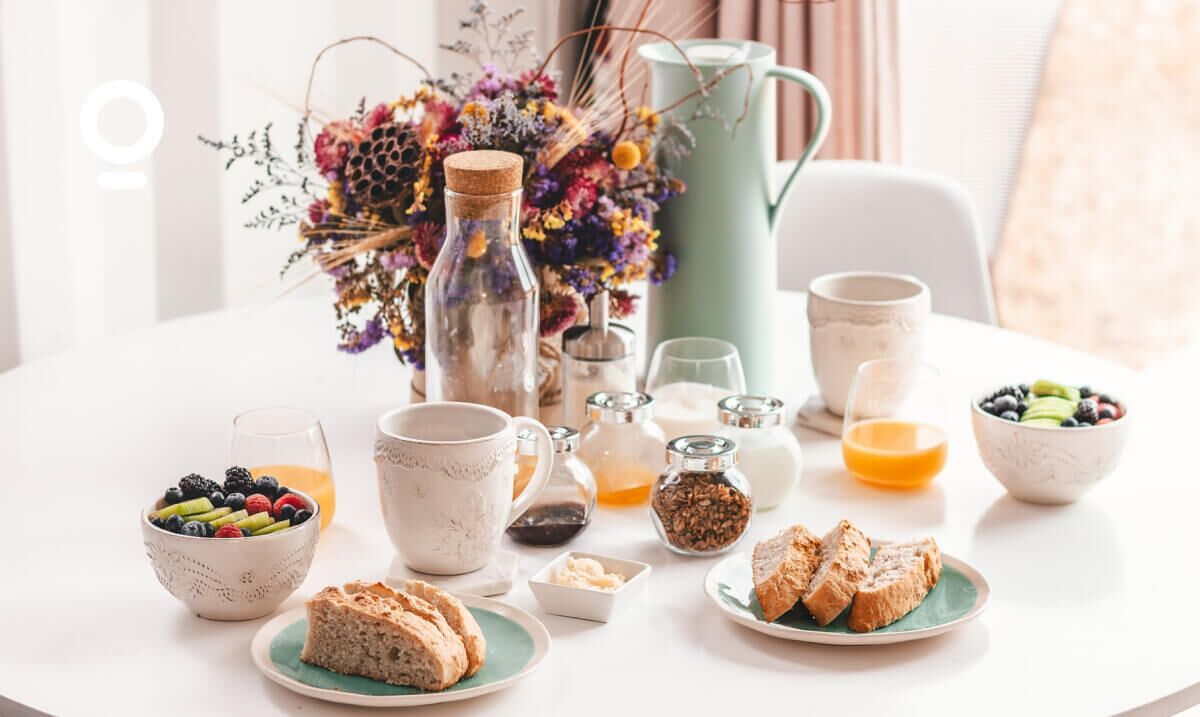 Una mesa de desayuno con diversas opciones de comida, como frutas, pan y bebidas.