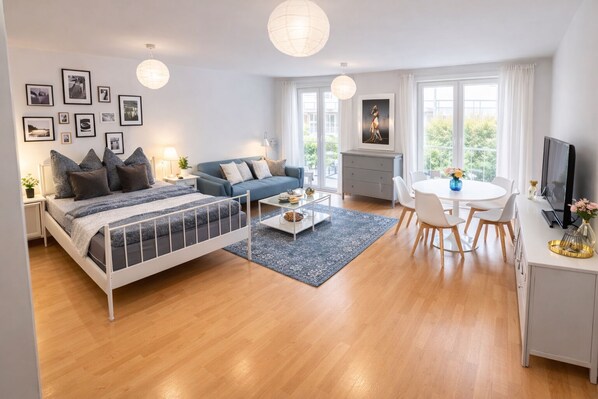 Una sala moderna con cama, sofá, mesa de centro y comedor.
