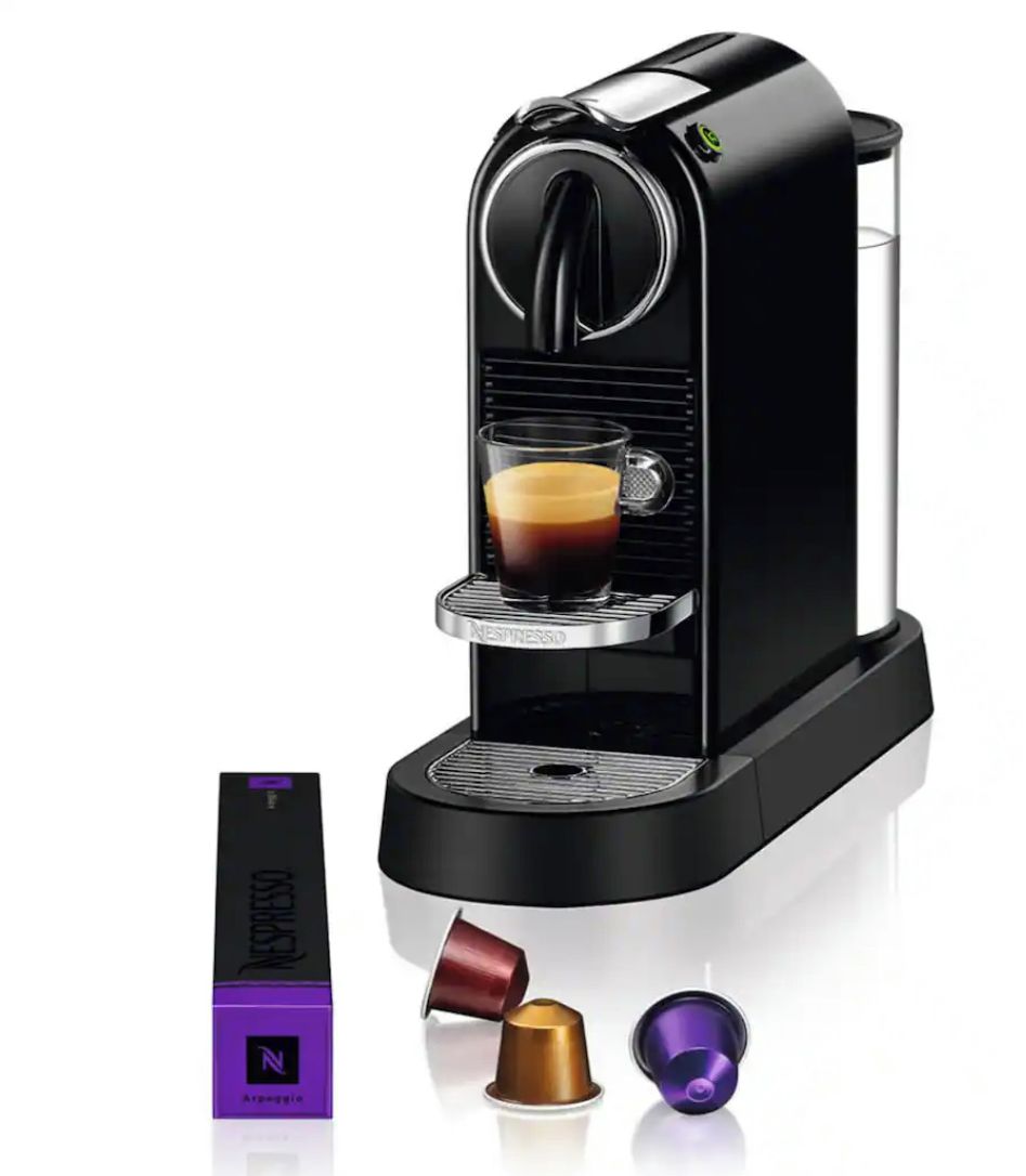 A Nespresso coffee machine with a cup of coffee, a Nespresso capsule, and two capsules.
