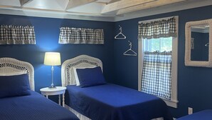A room with three beds, a lamp, and a window with curtains.