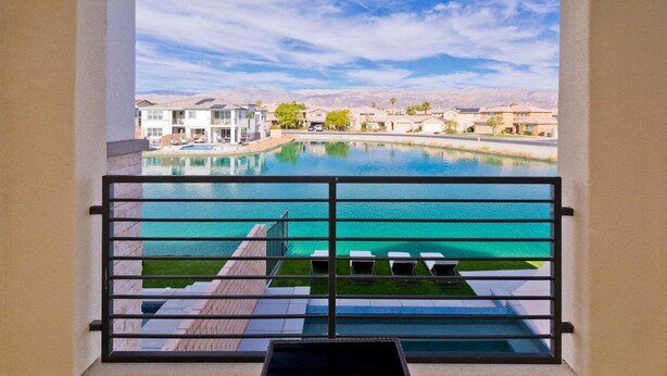 Vista de una piscina desde un balcón, con cielo despejado y edificios al fondo.