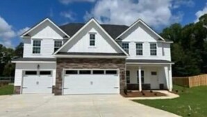 A two-story house with a stone facade, two garages, and a covered front porch. - Spacious & Cozy Turnkey Master’s Tournament Rental with Concierge Level Service (Grovetown)