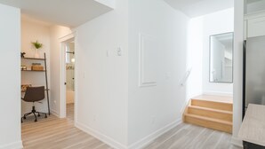 A modern interior with a wooden floor, white walls, and a staircase leading to an upper level. - Cozy Haven in Port Hope: Explore, Relax, Recharge (Port Hope)